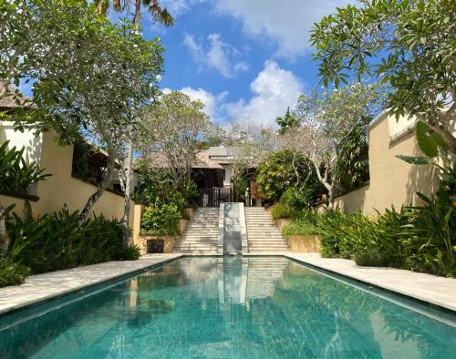 una piscina frente a una casa con árboles en Jimbaran BeachStroll Villa (3BR) en Jimbaran