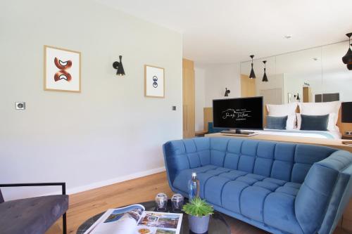 a living room with a blue couch and a bed at Hôtel Sainte Victoire in Vauvenargues