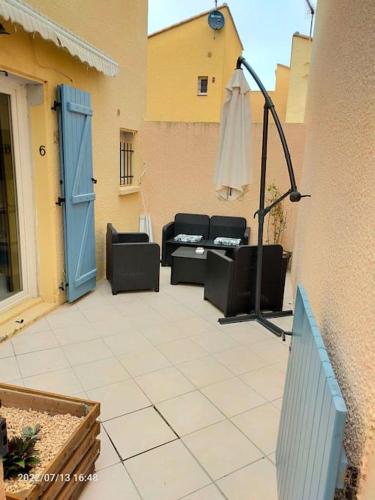 een patio met stoelen en een parasol naast een gebouw bij Appartement en résidence avec parking in Le Barcarès
