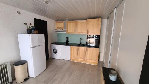 een kleine keuken met een witte koelkast en houten kasten bij Appartement en résidence avec parking in Le Barcarès