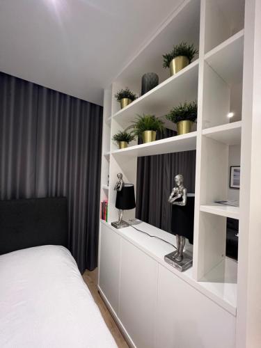 a bedroom with a bed and shelves with plants at LHR Apartments in London