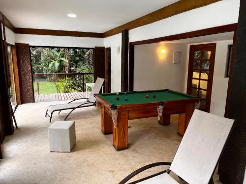 Villa Aconchego Corrêas Itaipava في بتروبوليس: غرفة مع طاولة بلياردو وكرسيين