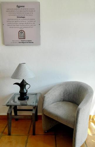 a living room with a chair and a table with a lamp at Hotel La Lejona in San Miguel de Allende