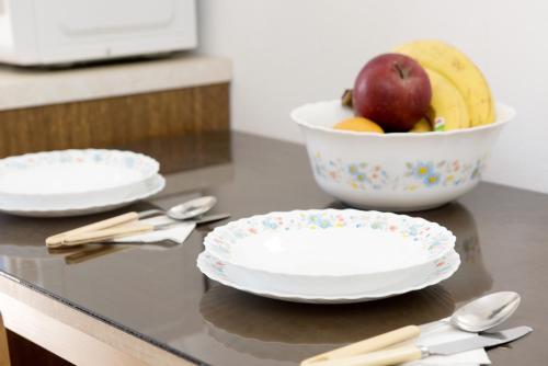 two white plates and a bowl of fruit on a counter at Maria Studios & Apartments in Kremasti