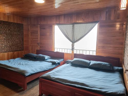 2 Betten in einem Zimmer mit Fenster in der Unterkunft May Kim Ta Phin Homestay in Sa Pa