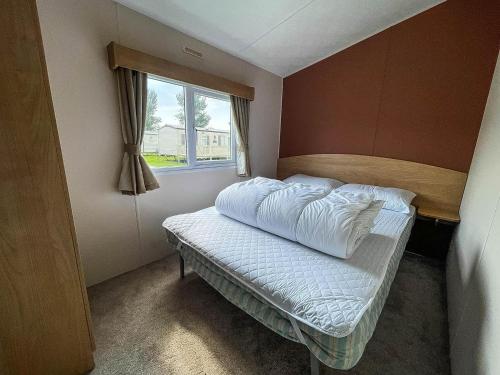 Cama en habitación con ventana en Homely 8 Berth Caravan In Southview Holiday Park, Ref 33048tc en Skegness