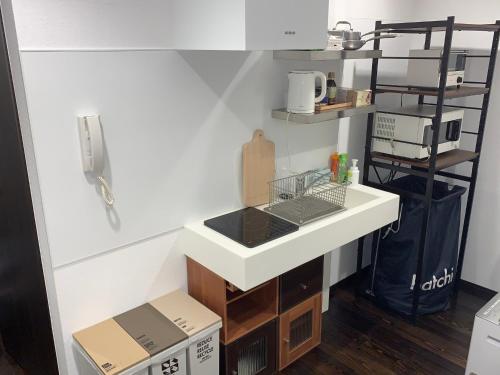 uma cozinha com um lavatório branco e uma prateleira em Shinjuku Miyabi Residence - Vacation STAY 94701 em Tóquio