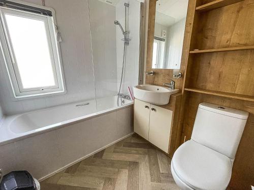 y baño con bañera, aseo y lavamanos. en Beautiful Lodge With Decking In Hunstanton At Manor Park Ref 23023w, en Hunstanton