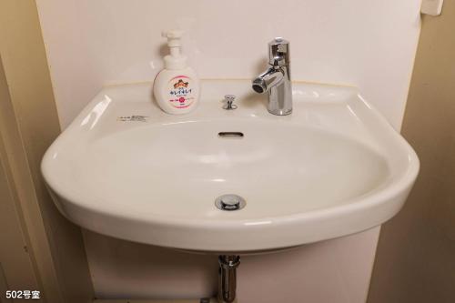 a white bathroom sink with a soap bottle on it at NanEi Building in Kagoshima