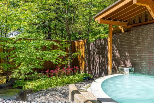 a backyard with a swimming pool and a wooden pergola at Kyukamura Nikko-Yumoto in Nikko