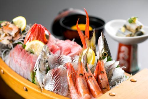 una bandeja de pescado y otros alimentos en una mesa en Hotel Kan-ichi, en Atami