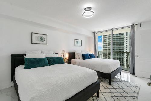 two beds in a room with a window at Awesome Penthouse Apt Brickell W/Pool in Miami