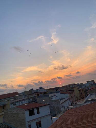 a group of buildings with birds flying in the sky at Cusumano house in Trappeto