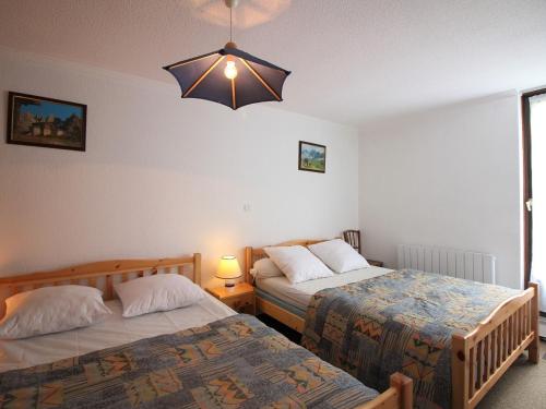 une chambre avec deux lits et un lustre dans l'établissement Appartement T3 au Mont-Dore - Balcon, Parking, Proche Centre Ville, 6 Pers, Charges Incluses - FR-1-415-147, à Le Mont-Dore