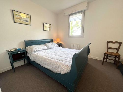 une chambre avec un lit, une chaise et une fenêtre dans l'établissement Appartement La Forêt-Fouesnant : port, plage et restaurants à pied, terrasse et parking - FR-1-481-146, à La Forêt-Fouesnant