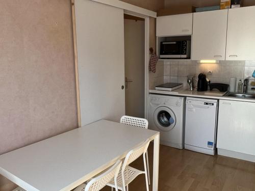 - une cuisine avec une table et des chaises blanches dans la chambre dans l'établissement Appartement T3 cosy, proche plage et thalasso, avec balcon et équipements modernes, WiFi inclus - FR-1-487-356, à Cabourg