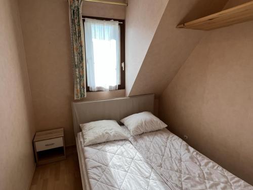 um pequeno quarto com uma cama e uma janela em Appartement Cabourg, 3 pièces, 4 personnes - FR-1-794-83 em Cabourg