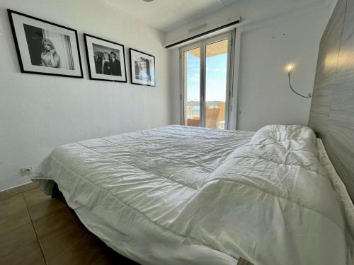 - une chambre avec un grand lit et des photos sur le mur dans l'établissement Superbe Apt 2P Front de Mer pour 4 pers avec Terrasse - Cavalaire-sur-Mer - FR-1-226B-162, à Cavalaire-sur-Mer