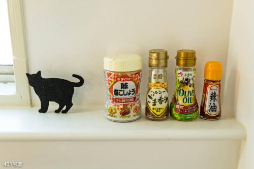 a black cat sitting on a shelf with condiments at NanEi Building in Kagoshima