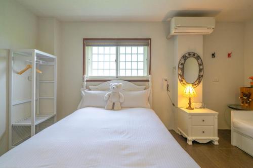 a teddy bear sitting on a bed in a bedroom at 稻哪趣田園民宿 平價villa in Dongshan