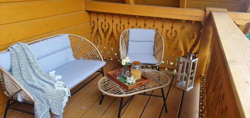 a porch with two chairs and a couch and a table at Apartamenty na Soszowie, Wisła - widokowe miejsce z Balią & Prywatną Sauną, obok stoku narciarskiego i Bike Parku, dla max 16 osób in Wisła