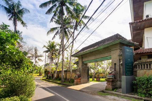 a building with a sign next to a street at Starloka Saba Bali Hotel in Blahbatu