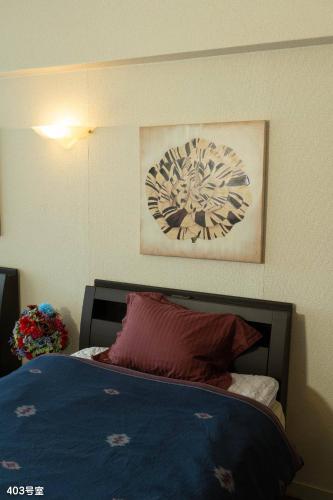 a bedroom with a bed and a painting on the wall at NanEi Building in Kagoshima