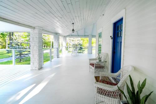 a porch with wicker chairs and a blue door at 1850 Catskills Farmhouse on 8 acres in E. Durham in East Durham