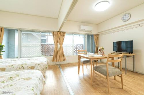 a room with a bed and a table and a tv at NanEi Building in Kagoshima