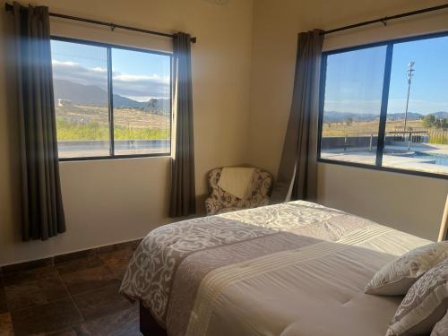 a bedroom with a bed and two large windows at Villas Persas by Jardin de Persia in Valle de Guadalupe