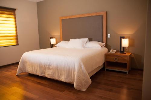 MBM Red Sun Hotel في مونتيري: غرفة نوم بسرير كبير عليها شراشف ووسائد بيضاء