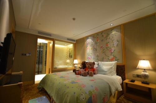 due orsacchiotti seduti su un letto in una camera d'albergo di Panyu Hotel a Canton