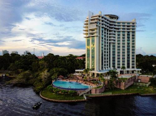 a hotel with a swimming pool next to a building at Flat Hotel Tropical Executive Praia Ponta Negra in Manaus