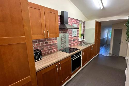 a kitchen with wooden cabinets and a brick wall at Palaz 7 - 5 bedroom house in Edmonton