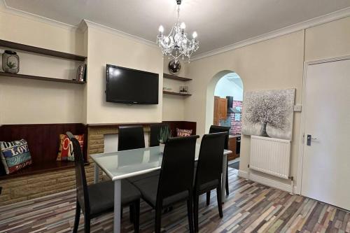 a dining room with a table and chairs and a tv at Palaz 7 - 5 bedroom house in Edmonton