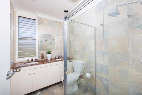 a bathroom with a toilet and a glass shower at Shoal Bay Shores, modern beachfront unit + Wifi in Nelson Bay