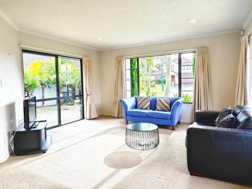 uma sala de estar com dois sofás azuis e uma televisão em Stunning Family Home em Auckland