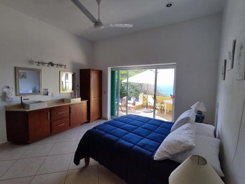 een slaapkamer met een blauw bed en een badkamer met uitzicht bij Casa las Palmas in Manzanillo
