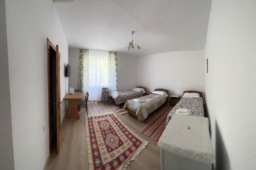 a room with two beds and a table in it at Meerim Murok in Bosteri