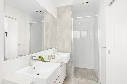 La salle de bains blanche est pourvue d'un lavabo et d'une douche. dans l'établissement Blue Lagoon Villas, à Trinity Beach