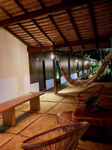 a hammock in a pavilion with a bench and chairs at Recanto Alter do Chão in Alter do Chao
