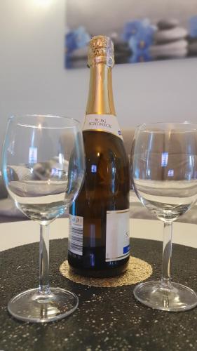 two wine glasses sitting next to a bottle of wine at Apartament w Kwiatki in Międzyzdroje