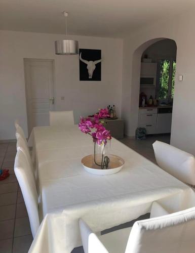 une table blanche avec un vase de fleurs sur elle dans l'établissement Villa Superbe Vue, à La Bruguière