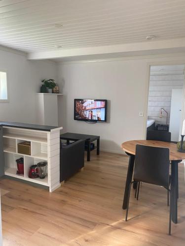 een woonkamer met een tafel en een tv aan de muur bij Mysig källarlägenhet i Lindvallen in Sälen