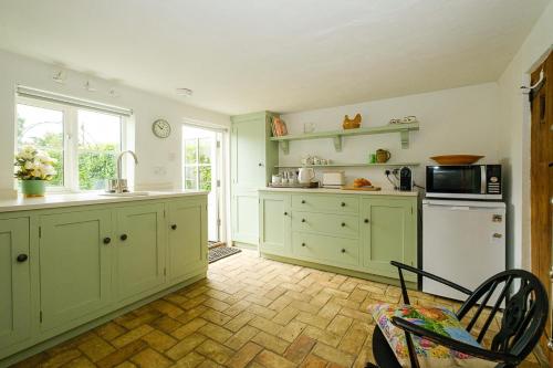 a kitchen with green cabinets and a sink and a microwave at 5 Mariners View in Friston
