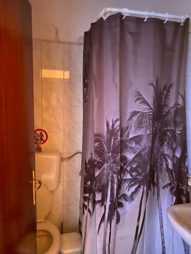 a bathroom with a shower curtain with palm trees at Lydia Rooms in Therma