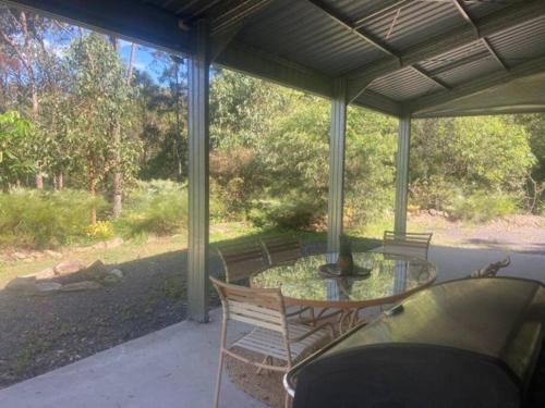 a patio with a glass table and chairs on a porch at Austinville Hinterland Chalet in Neranwood