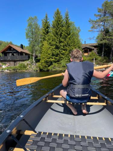 a man sitting in a boat with a paddle at Holiday cottage with sauna close to Kjeragbolten-Bedding included in Tjørhom
