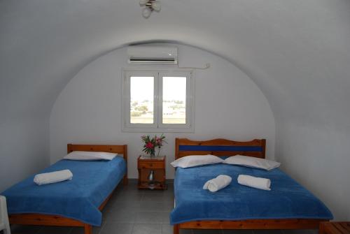 two beds in a room with a window at Apollo Rooms in Perissa