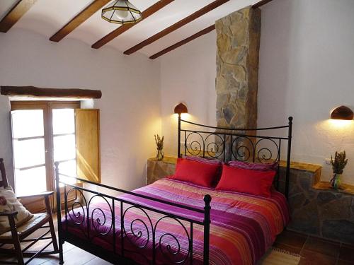 een slaapkamer met een bed met rode kussens erop bij Casas Rurales Cortijo Leontino in Taberno